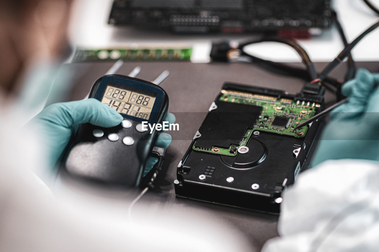 Cropped image of electrician repairing electrical equipment on table