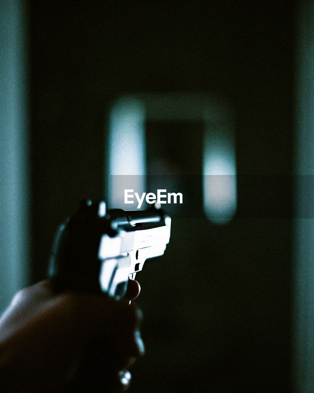 Close-up of person holding gun in darkroom