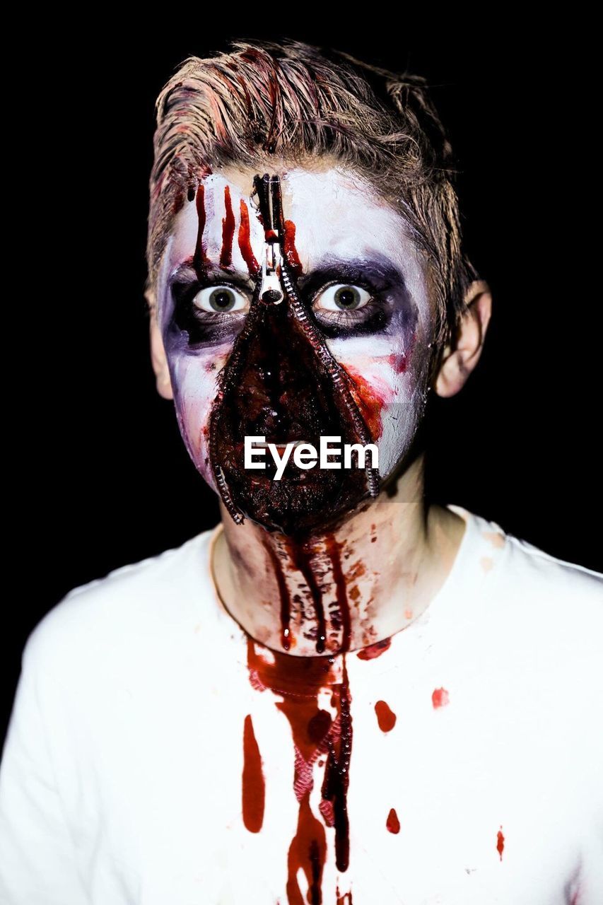 Digitally generated image of young man with spooky make-up against black background