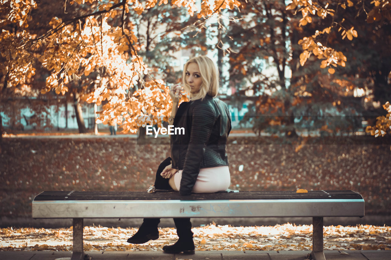 Portrait of beautiful woman sitting on bench at park