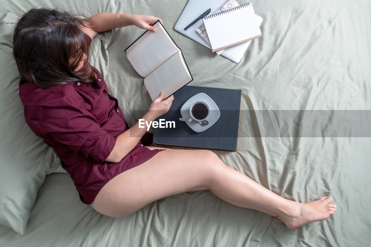 HIGH ANGLE VIEW OF WOMAN USING LAPTOP ON BED