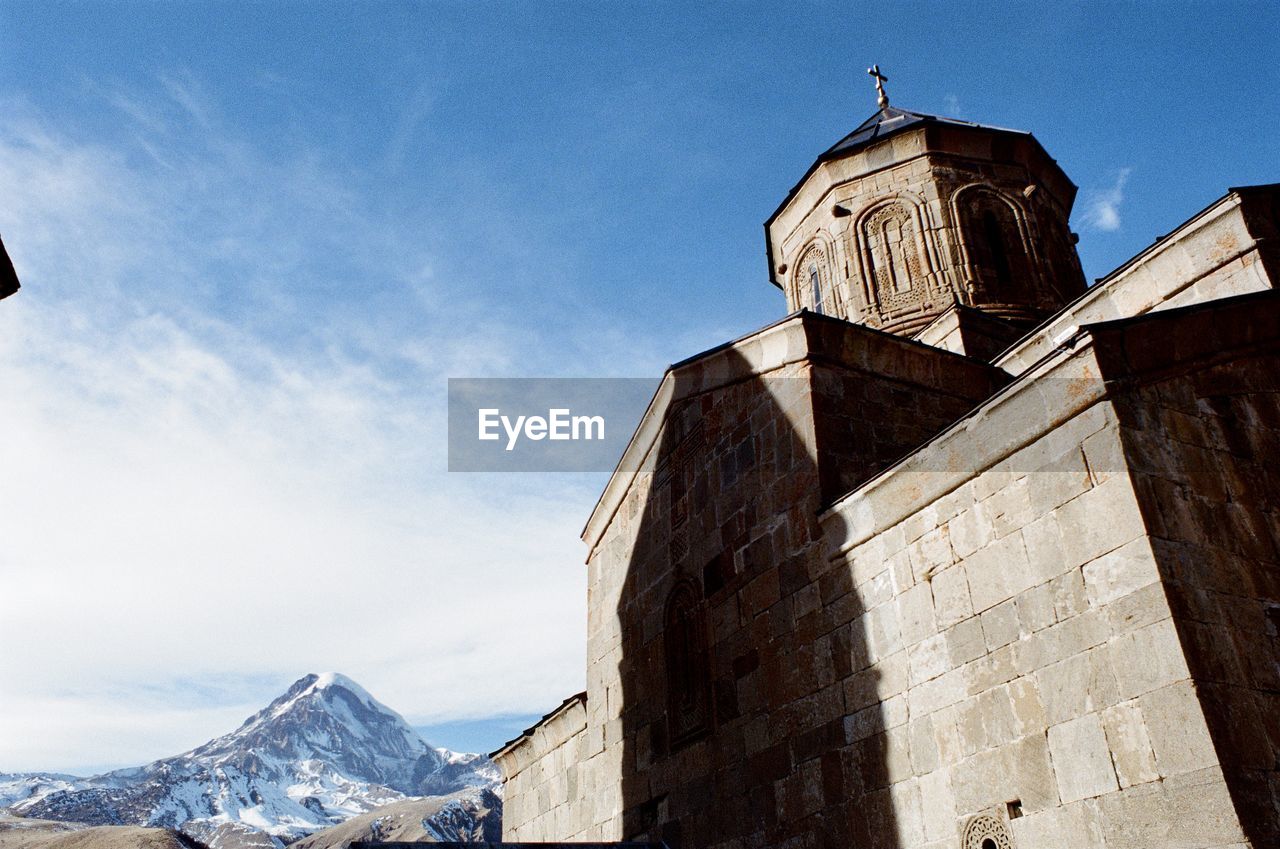 28mm angle view of gergeti trinity church against sky and glacier . 35mm ektar