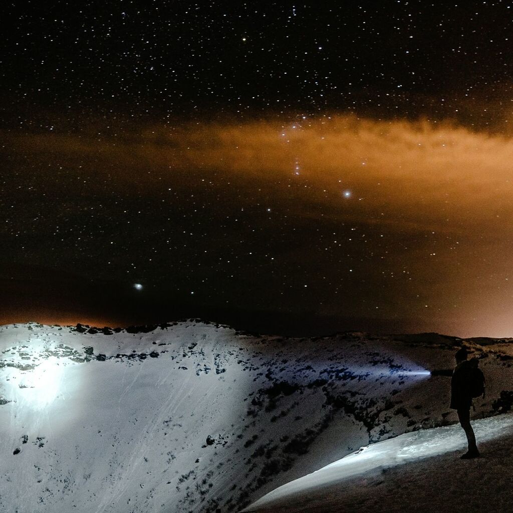 Side view of silhouette man hiking on mountain at night
