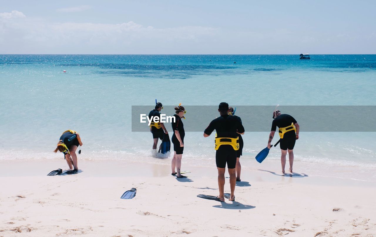 People with snorkel at beach against sky