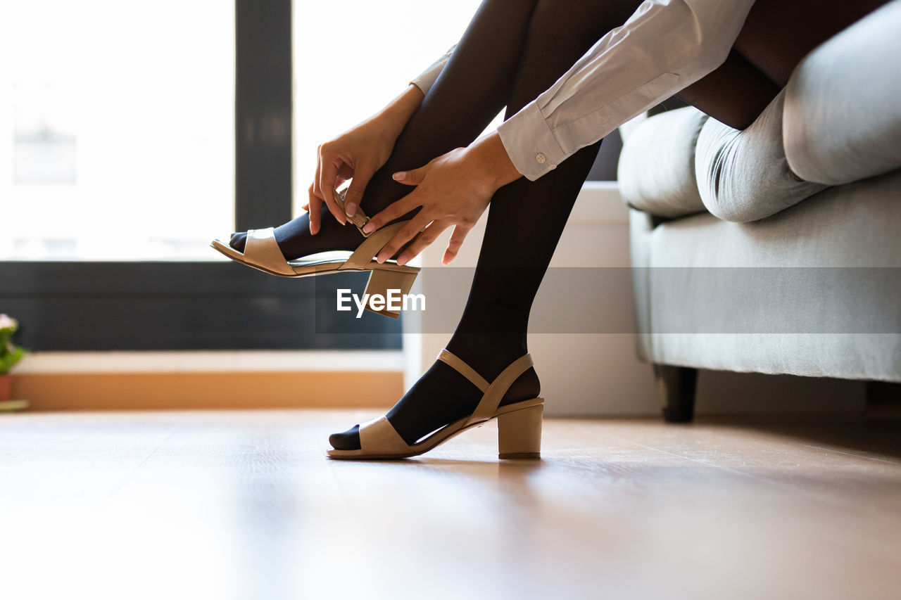 Young woman putting on her heels at home