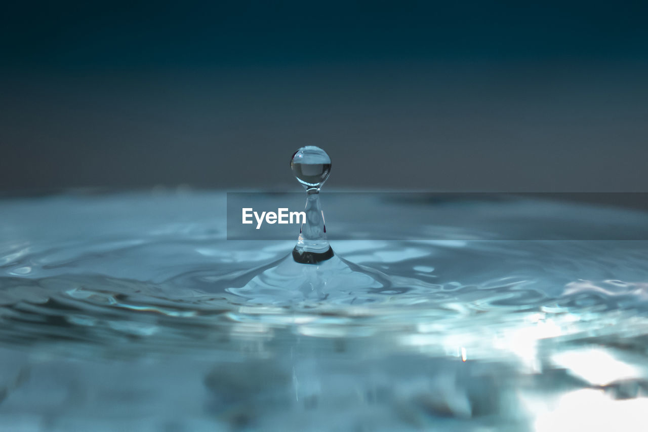 Water droplet rises after falling on blue surface