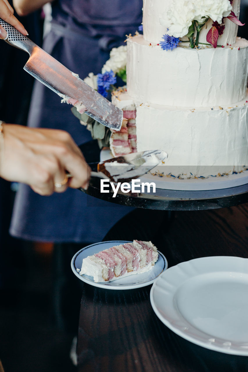 Cropped hands serving cake in plate at wedding ceremony