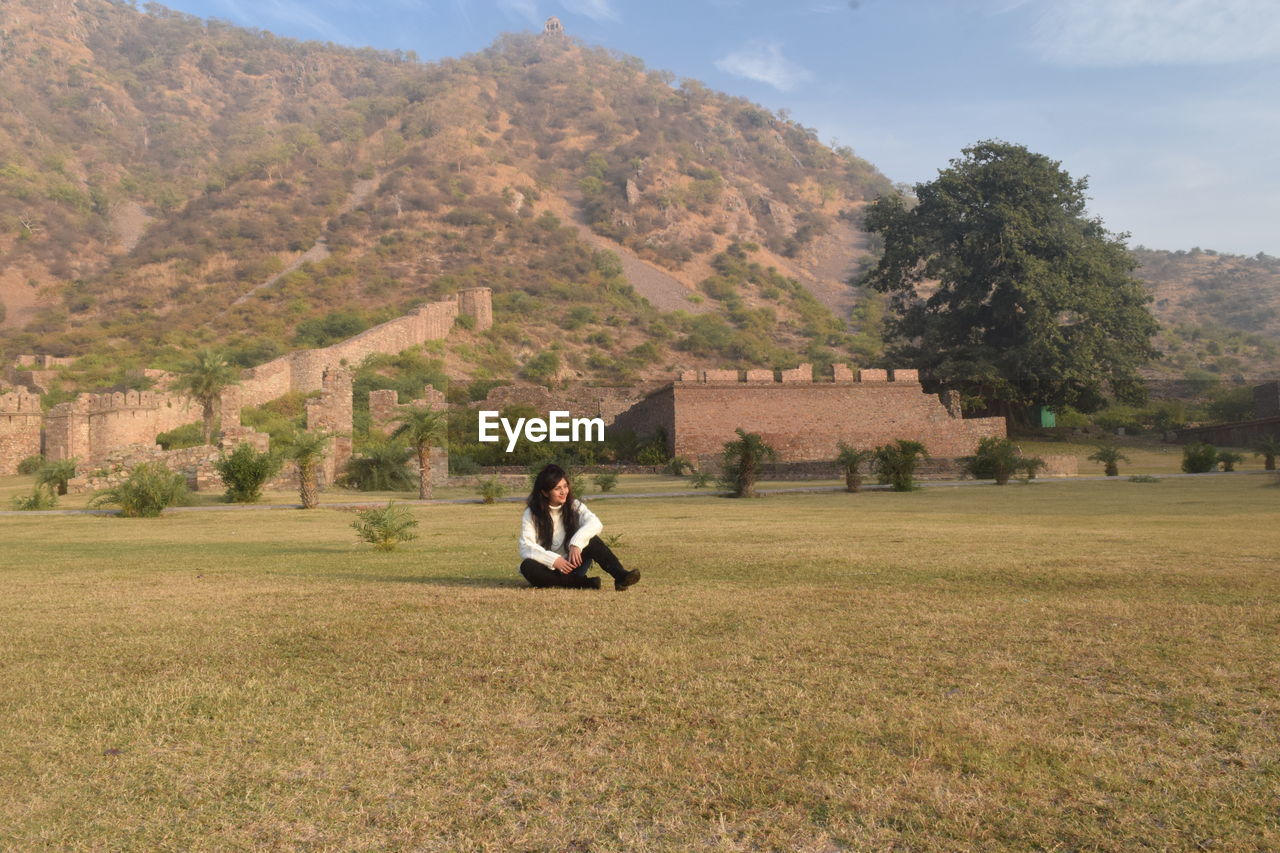 Man sitting on field against mountain