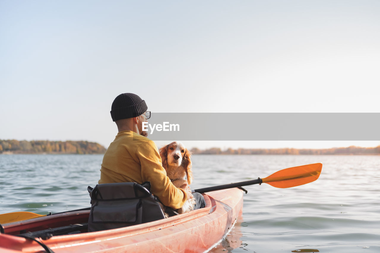 Man sitting in kayak with dog in sea