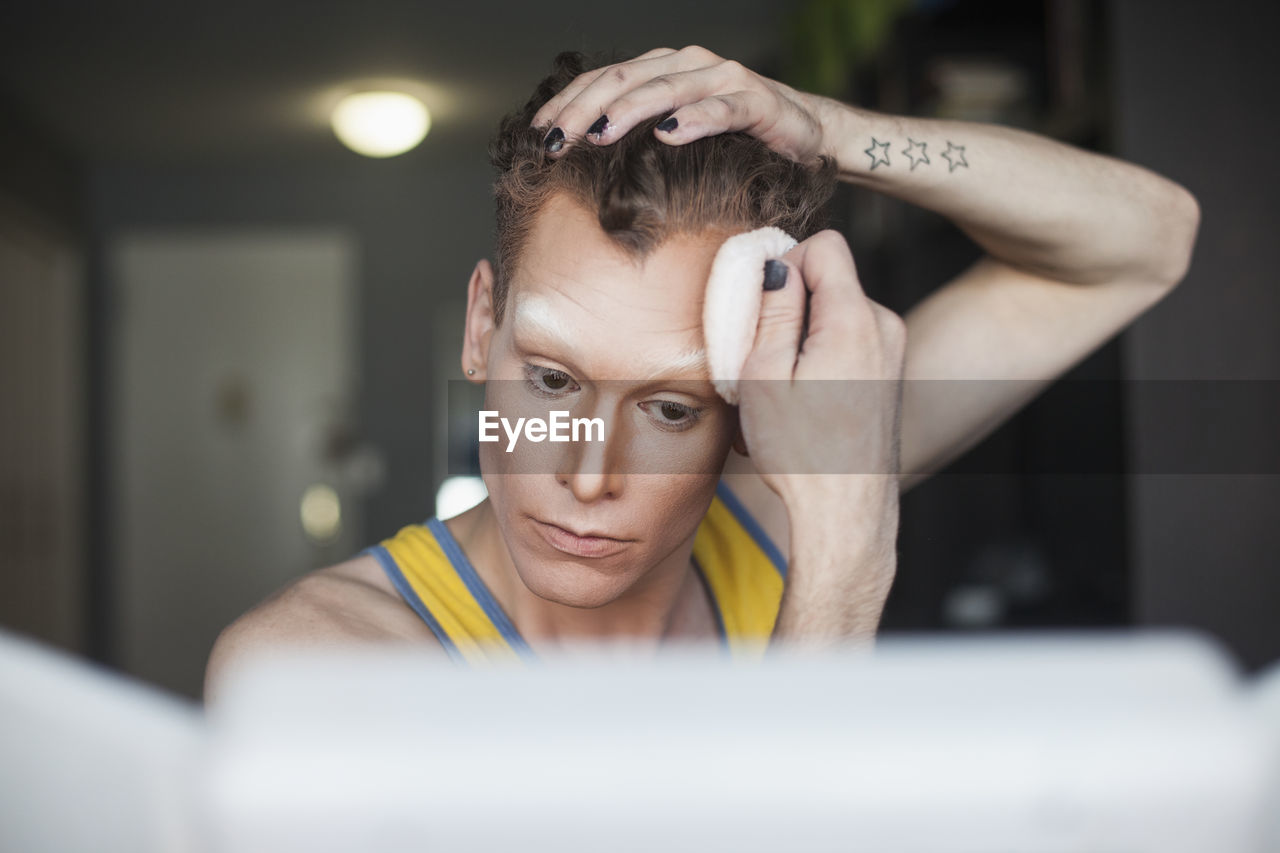 Young man applying pressed powder