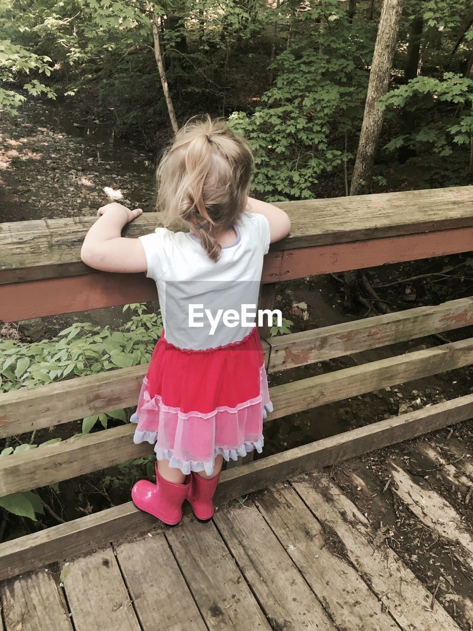 High angle view of girl standing on wooden railing