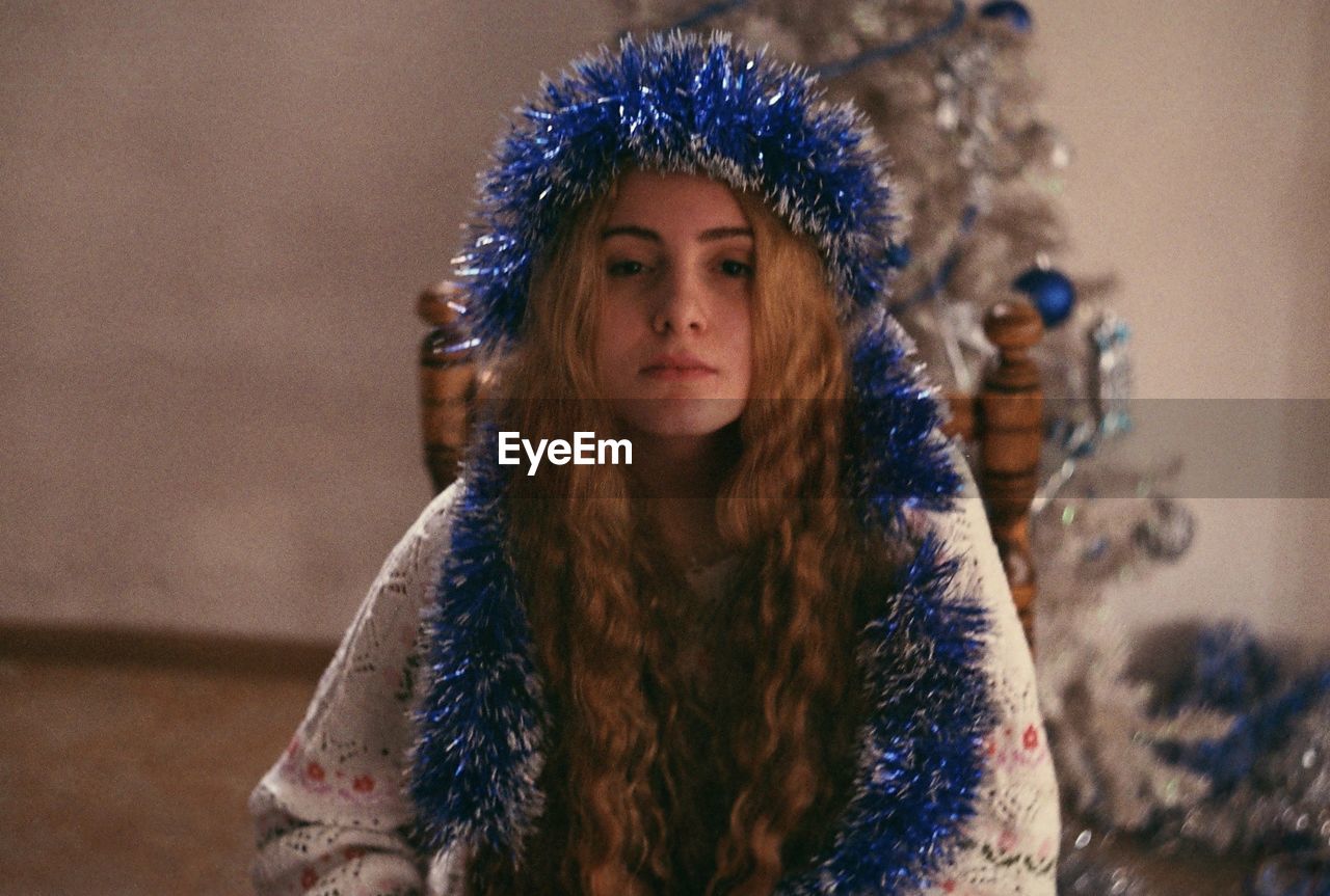 Young woman with blue tinsel while sitting at home