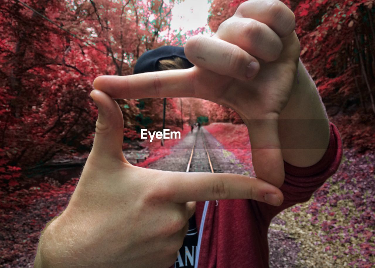 Digital composite image of railroad track seen through man hands