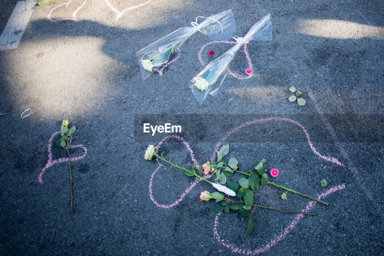 High angle view of flowers and bouquets on road with chalk drawing