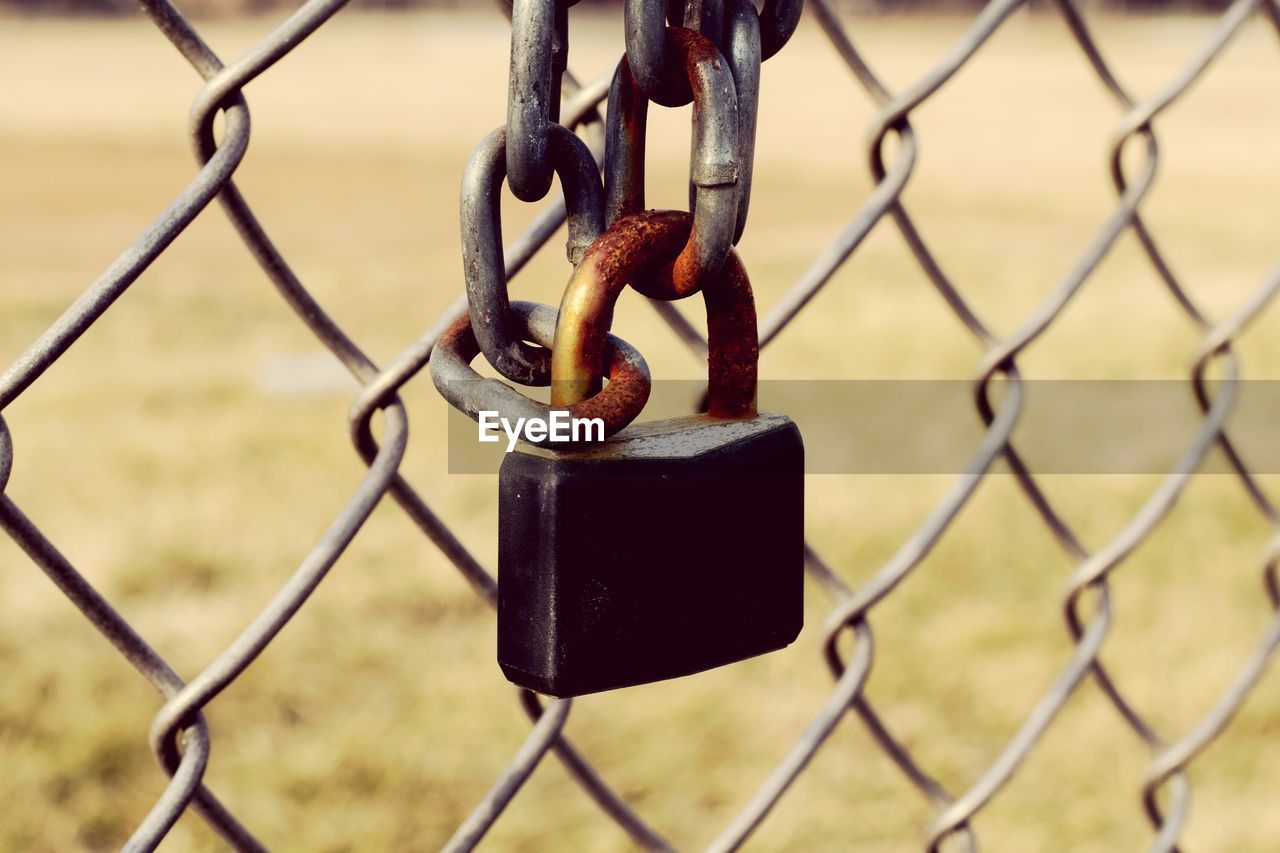 Close-up of padlock attached to chainlink fence