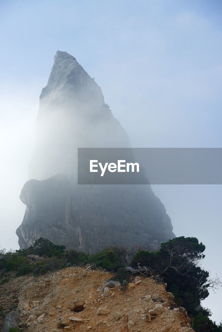 LOW ANGLE VIEW OF ROCKS ON MOUNTAIN AGAINST SKY