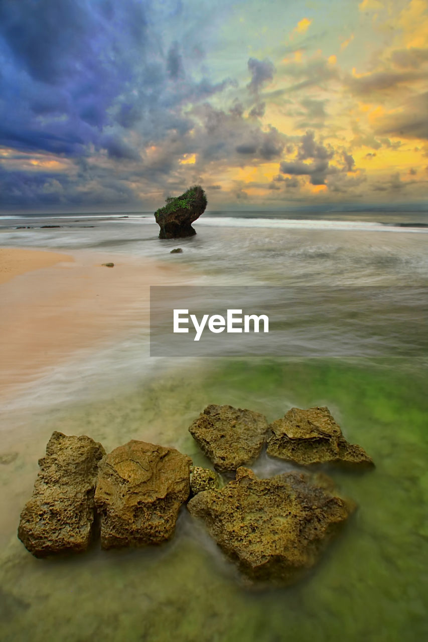 Close-up of rock on beach against sky during sunset