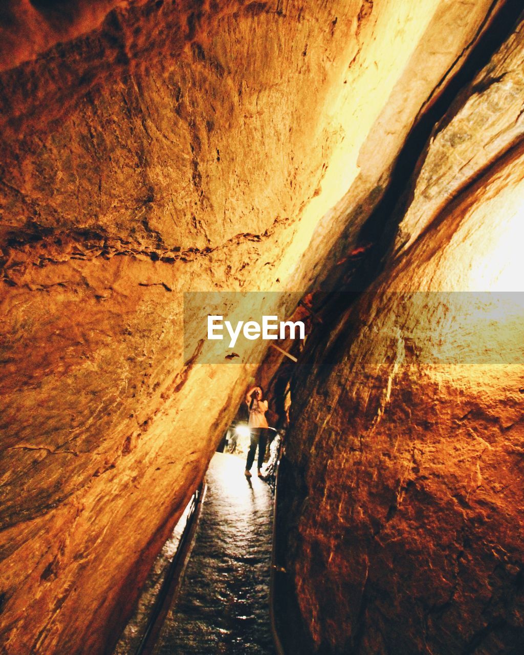 Woman photographing with camera seen through rock formations