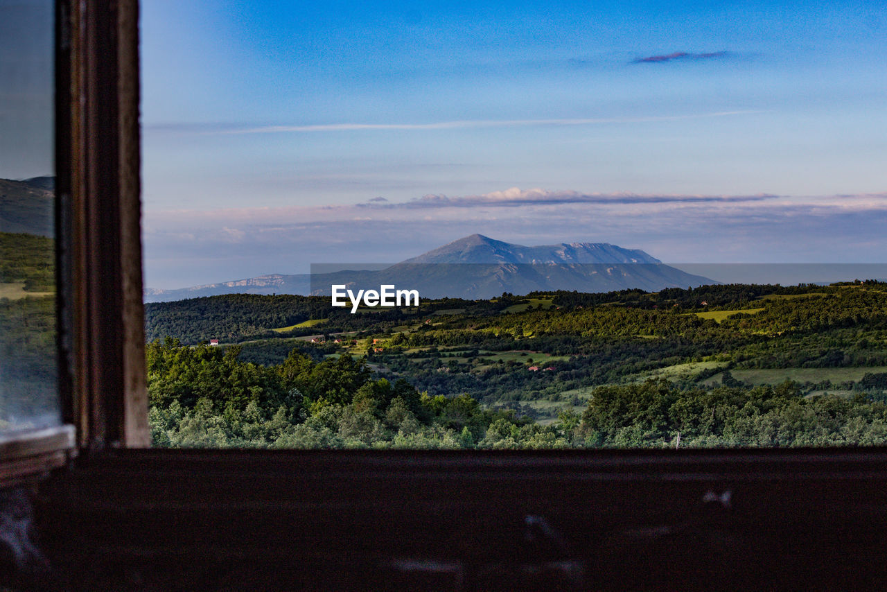 Scenic view of landscape against sky seen through window