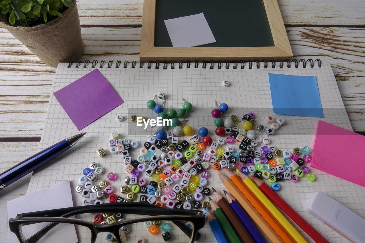 High angle view of alphabet beads with school supplies on table