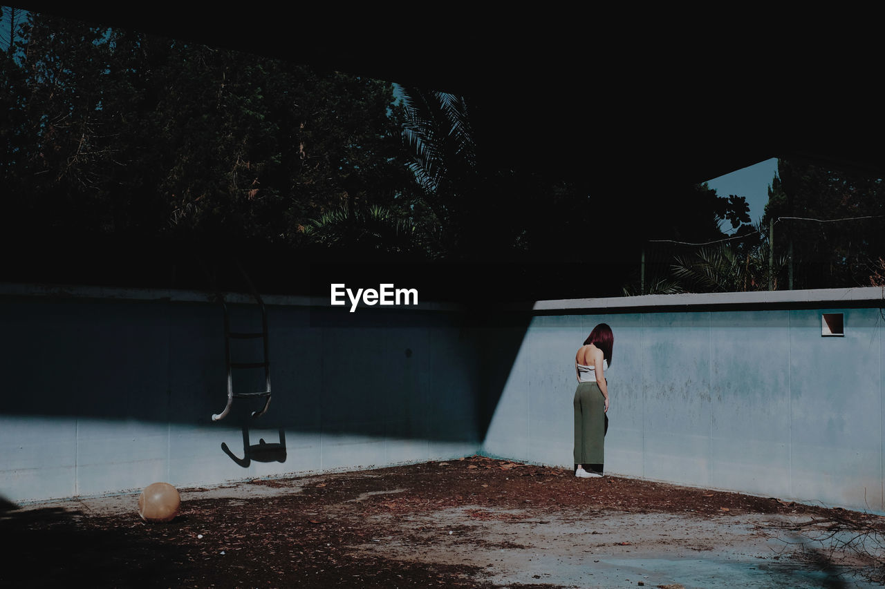Full length of woman standing in abandoned swimming pool