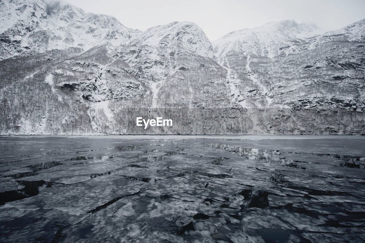 Frozen landscape against snowcapped mountains