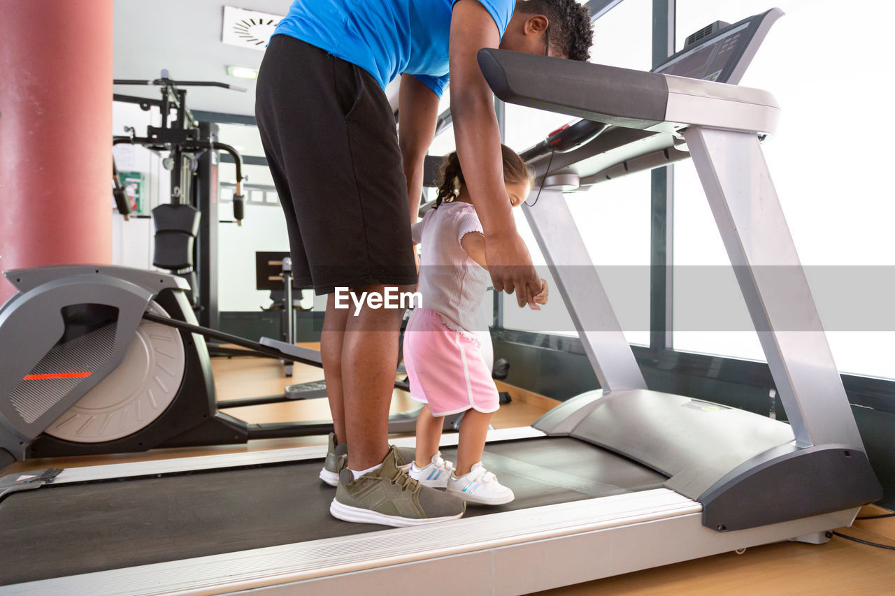 Crop dad exercising with daughter on treadmill