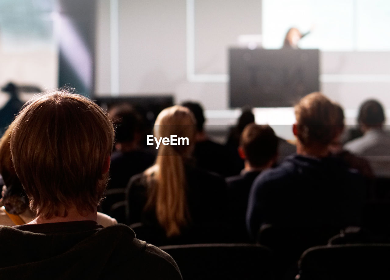 Rear view of students attending lecture in auditorium