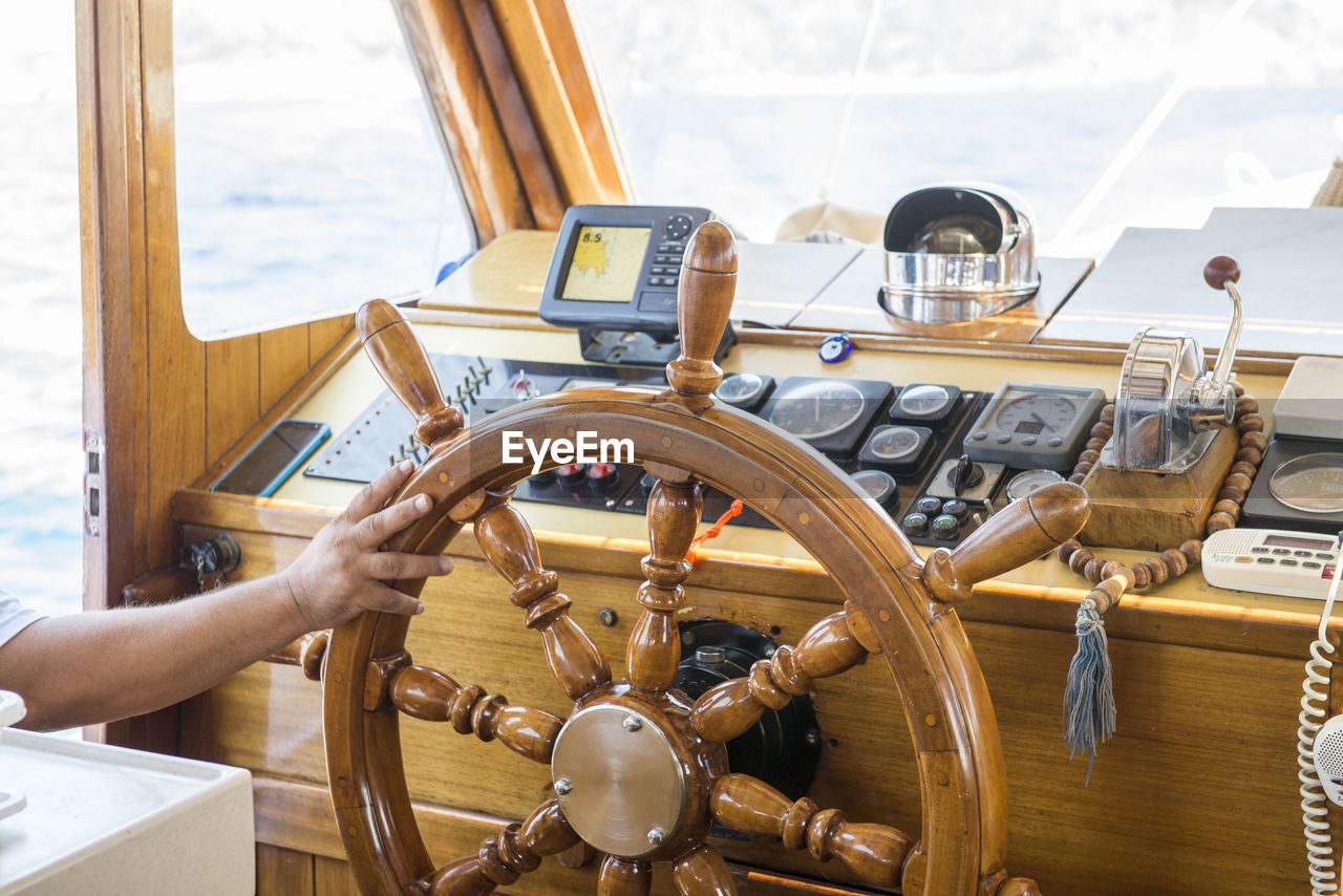 Cropped hand of man holding helm in boat