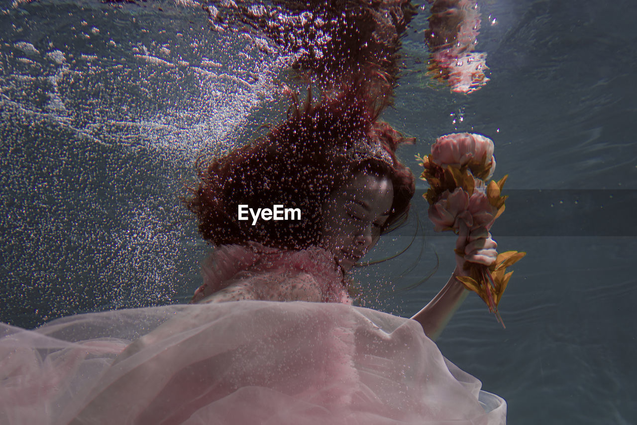 Woman holding flowers while swimming in pool