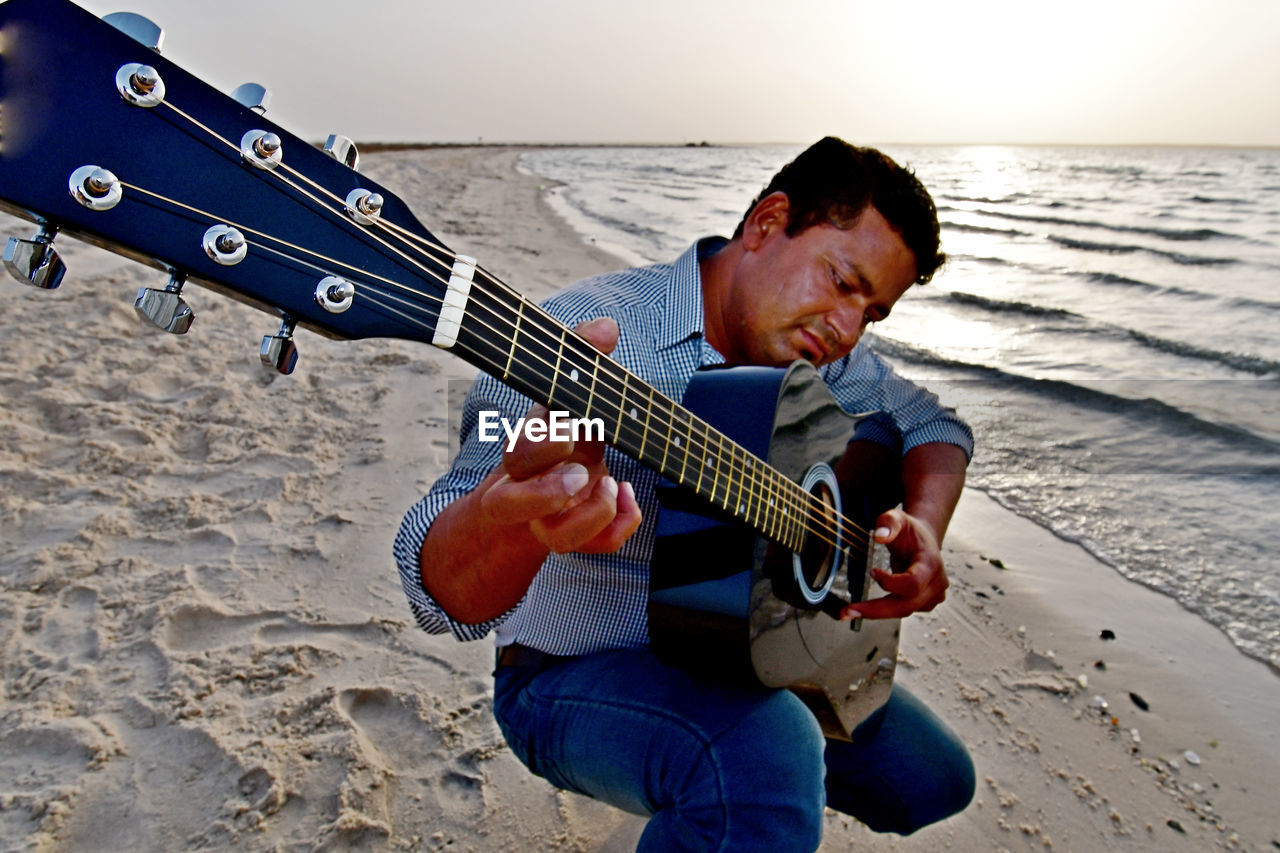 Man playing guitar at beach