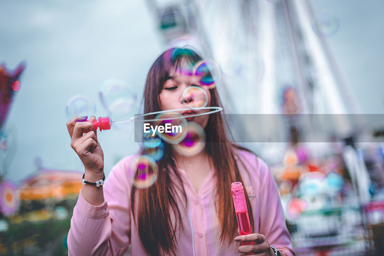 Woman Blowing Bubbles In City Id 128885643