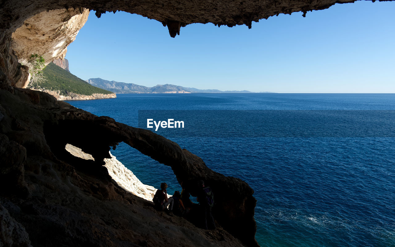 Scenic view of cave and sea against clear sky