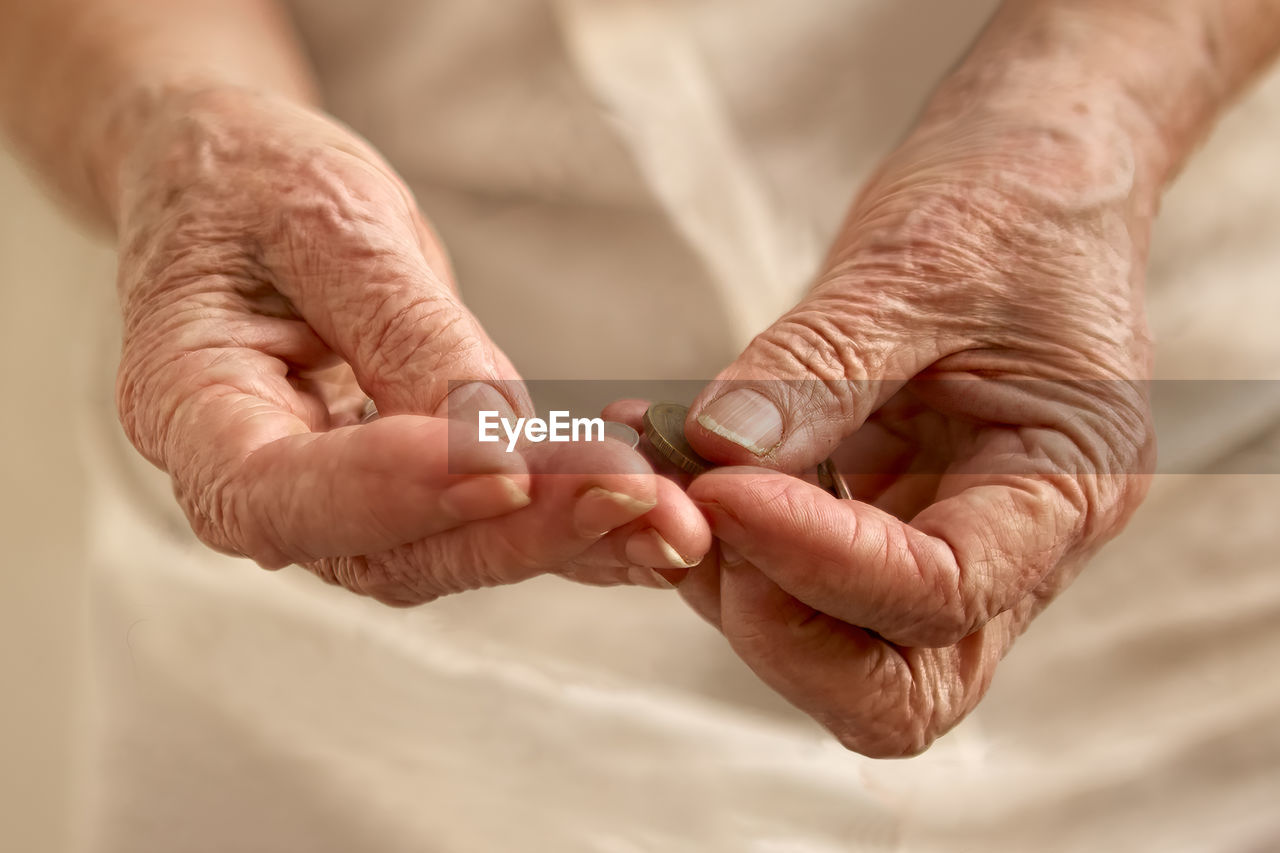 Old woman's wrinkled hands counting small coins