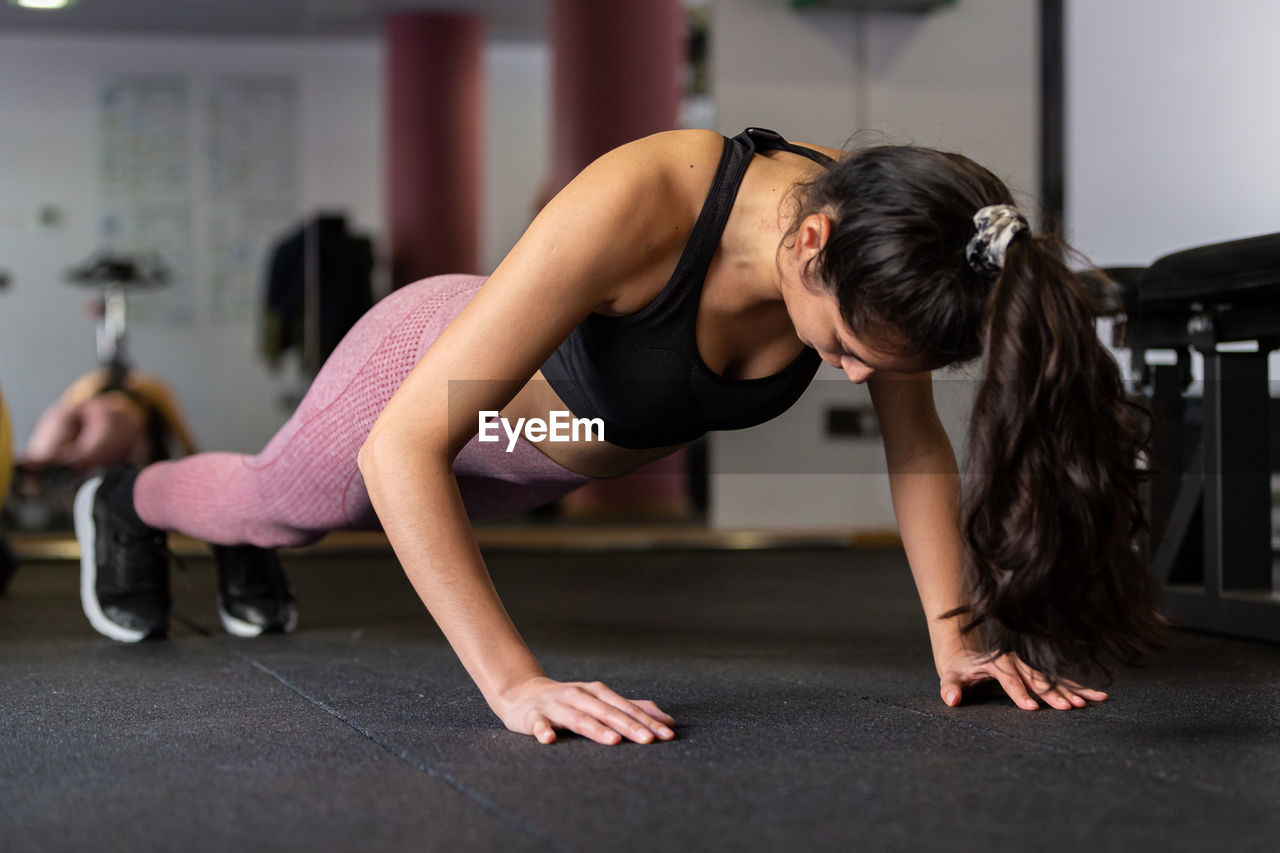 Young woman doing pushups in the gym