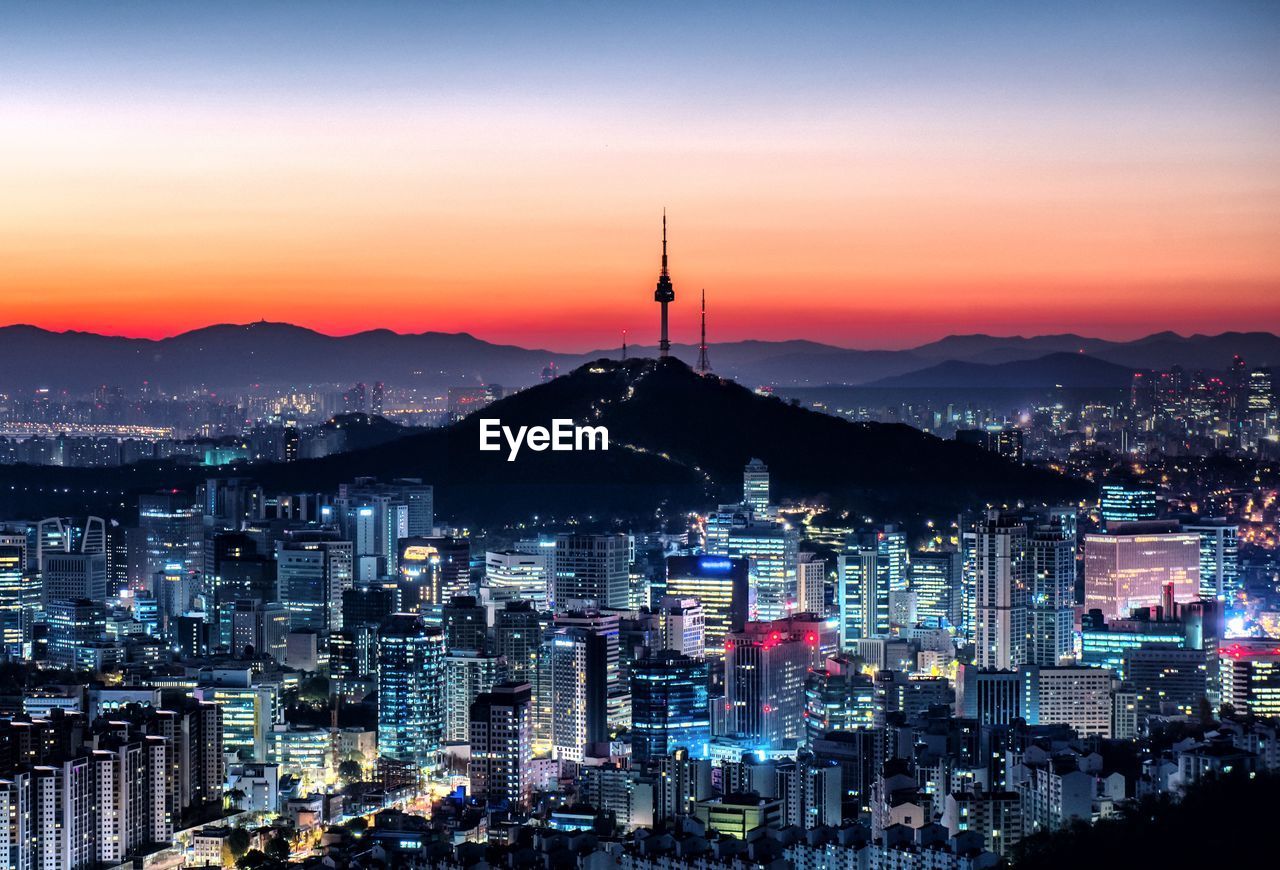 Illuminated city against sky during sunset