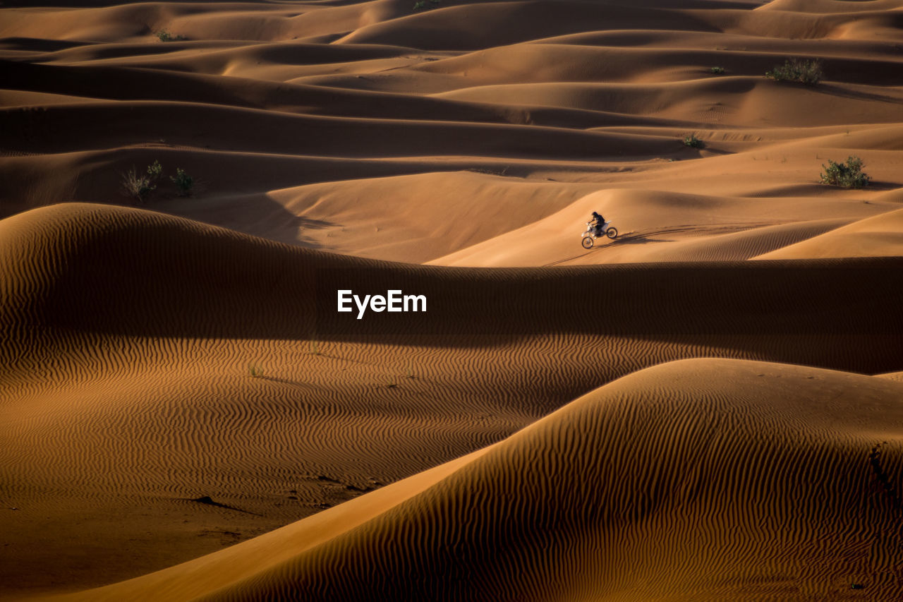 High angle view of man riding motorcycle on sand at desert
