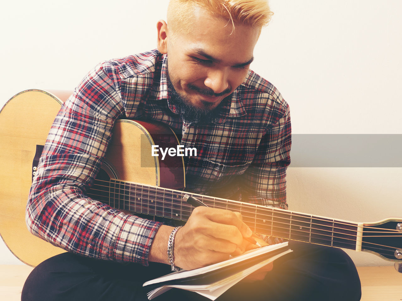 MIDSECTION OF MAN PLAYING GUITAR AT HOME