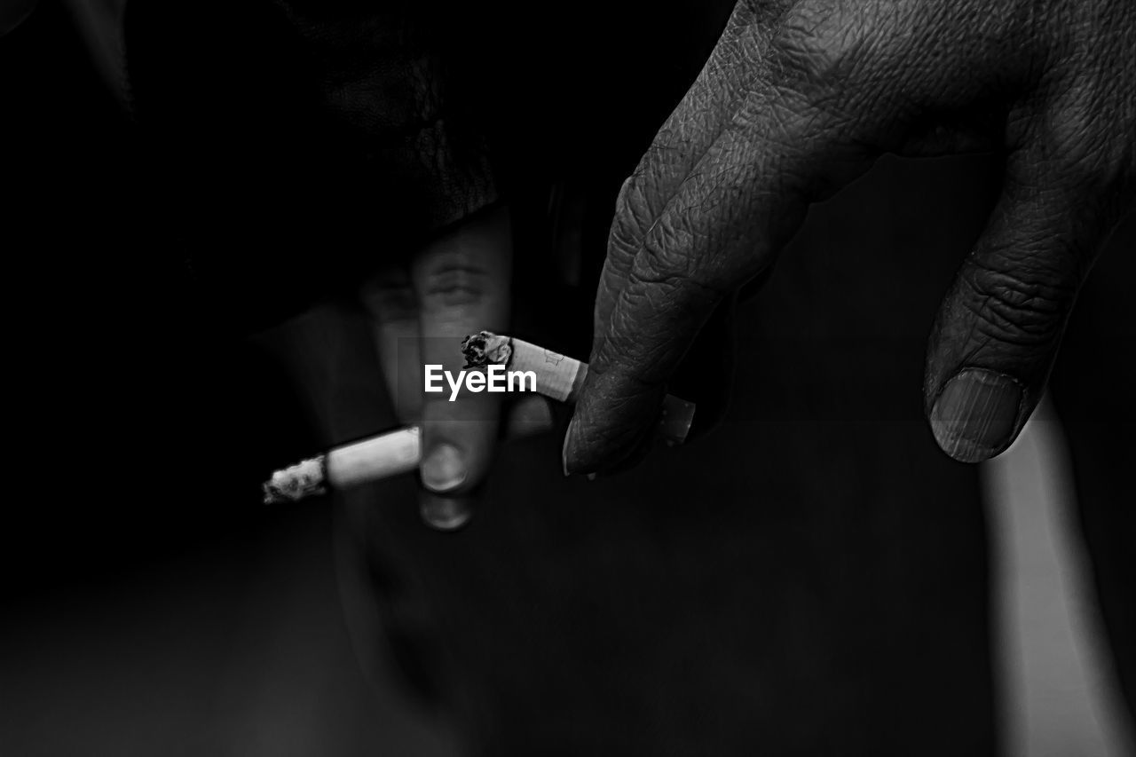Cropped hand of people holding cigarettes