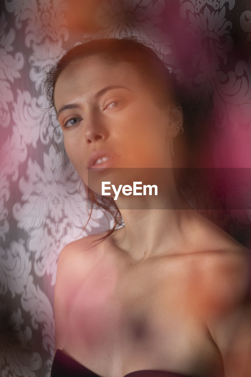 Close-up portrait of young woman against wall