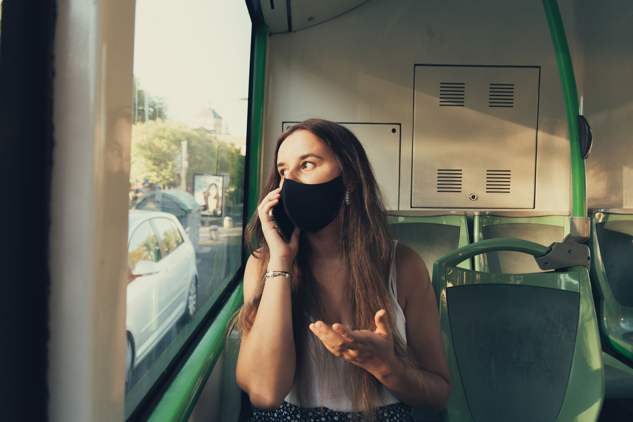 Girl in a mask talking on her phone on the city bus