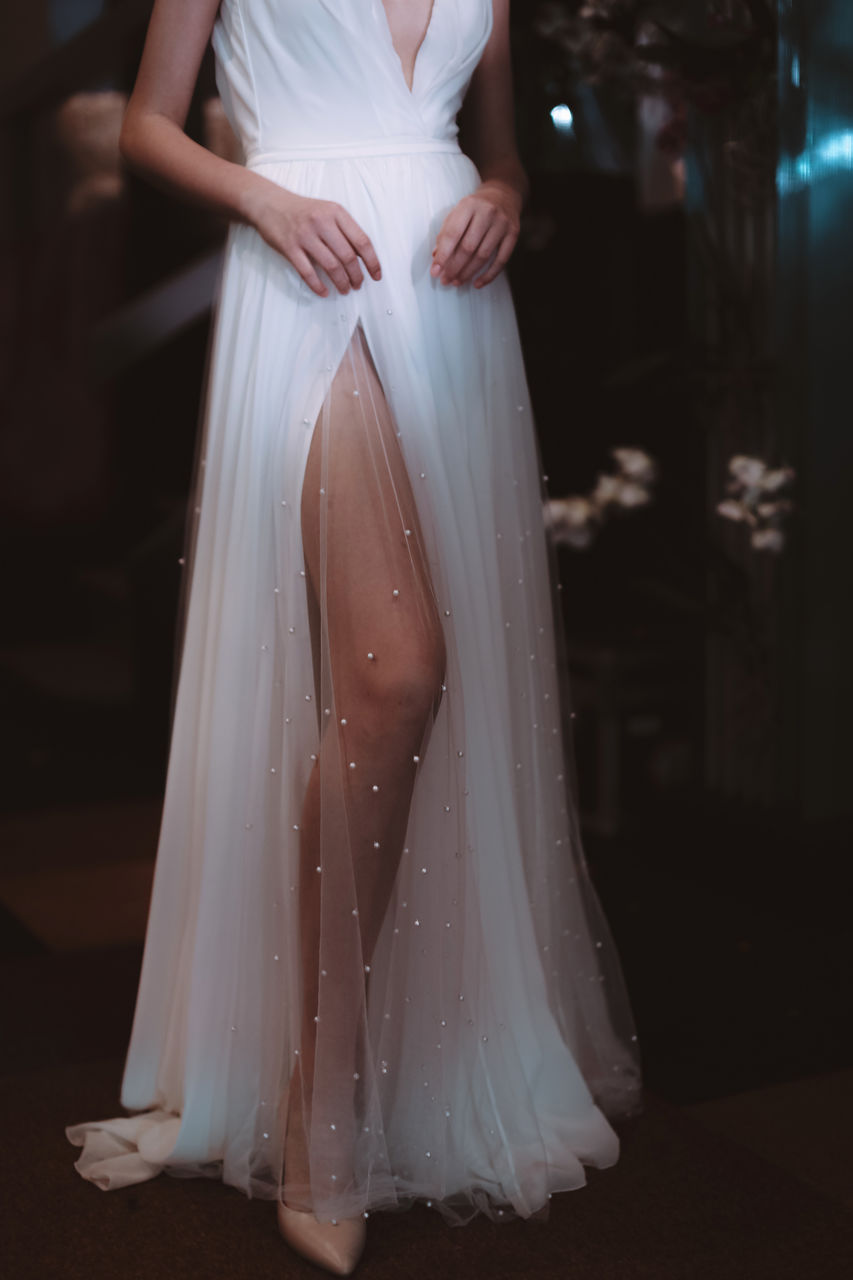 Cropped figure of model dressed in white long wedding dress.