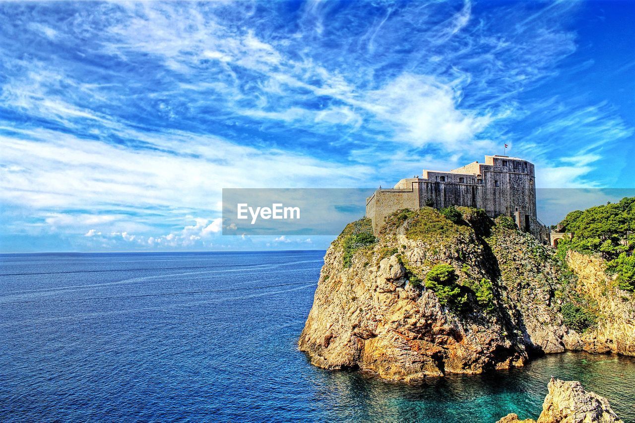 Scenic view of sea by rocks against sky