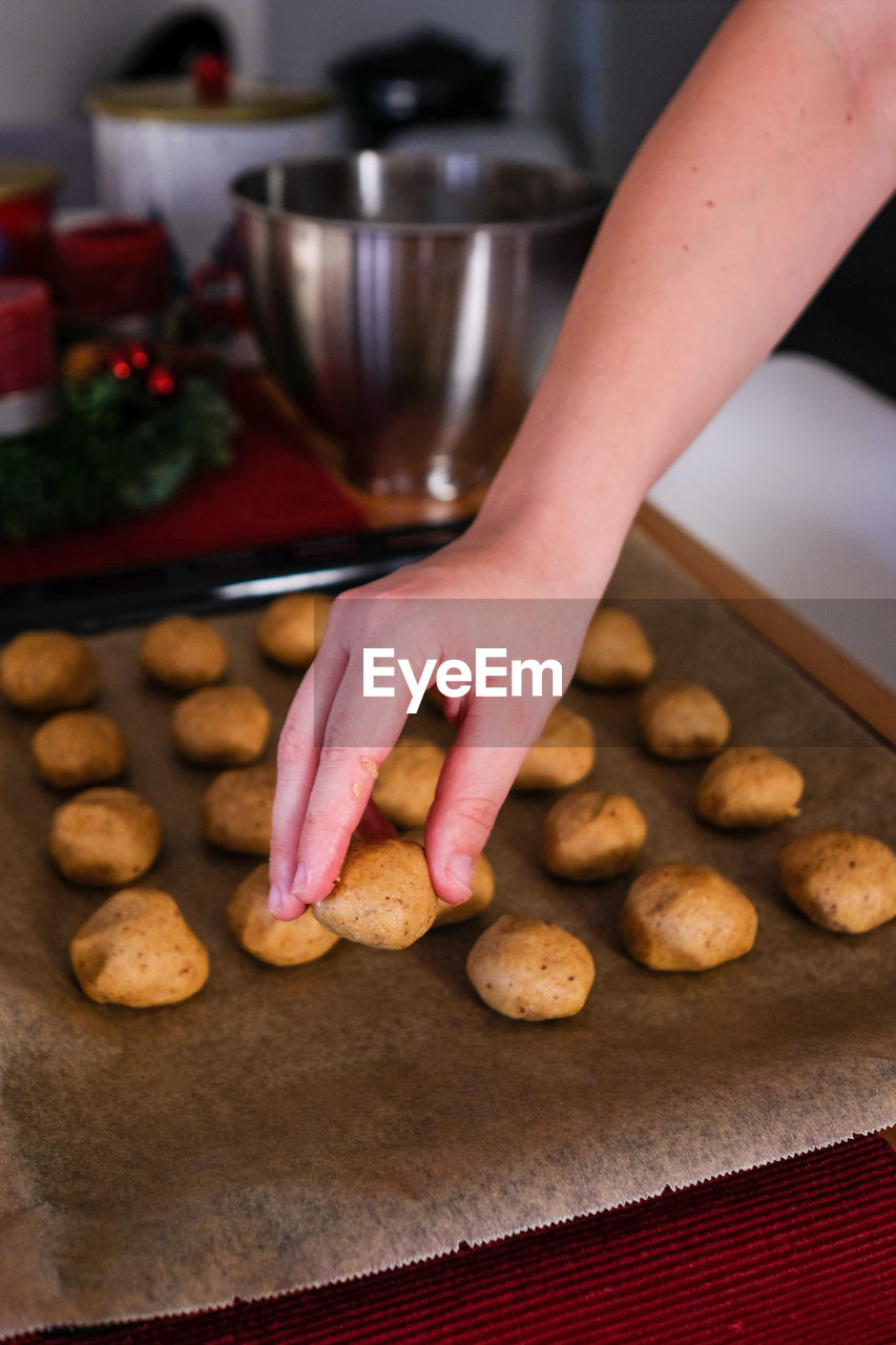 MIDSECTION OF PERSON HOLDING COOKIES IN KITCHEN AT HOME