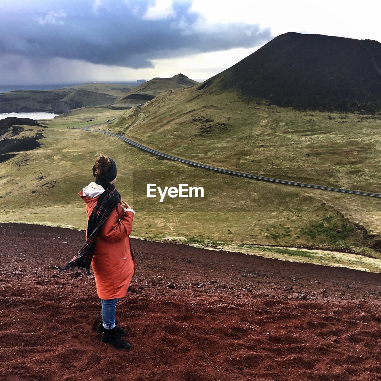 Full length of woman at vestmannaeyjar looking at mountain