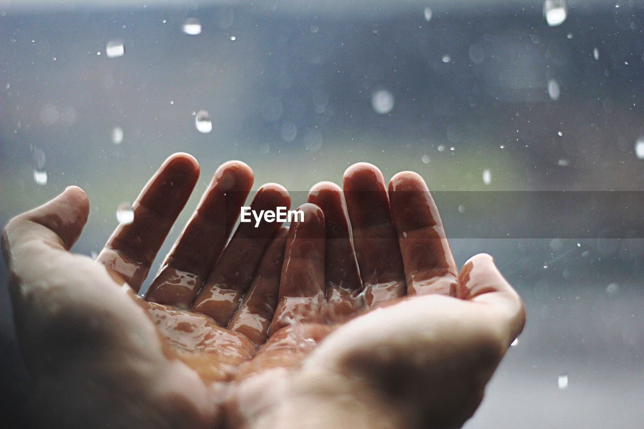 Cropped image of woman with hands cupped in rain