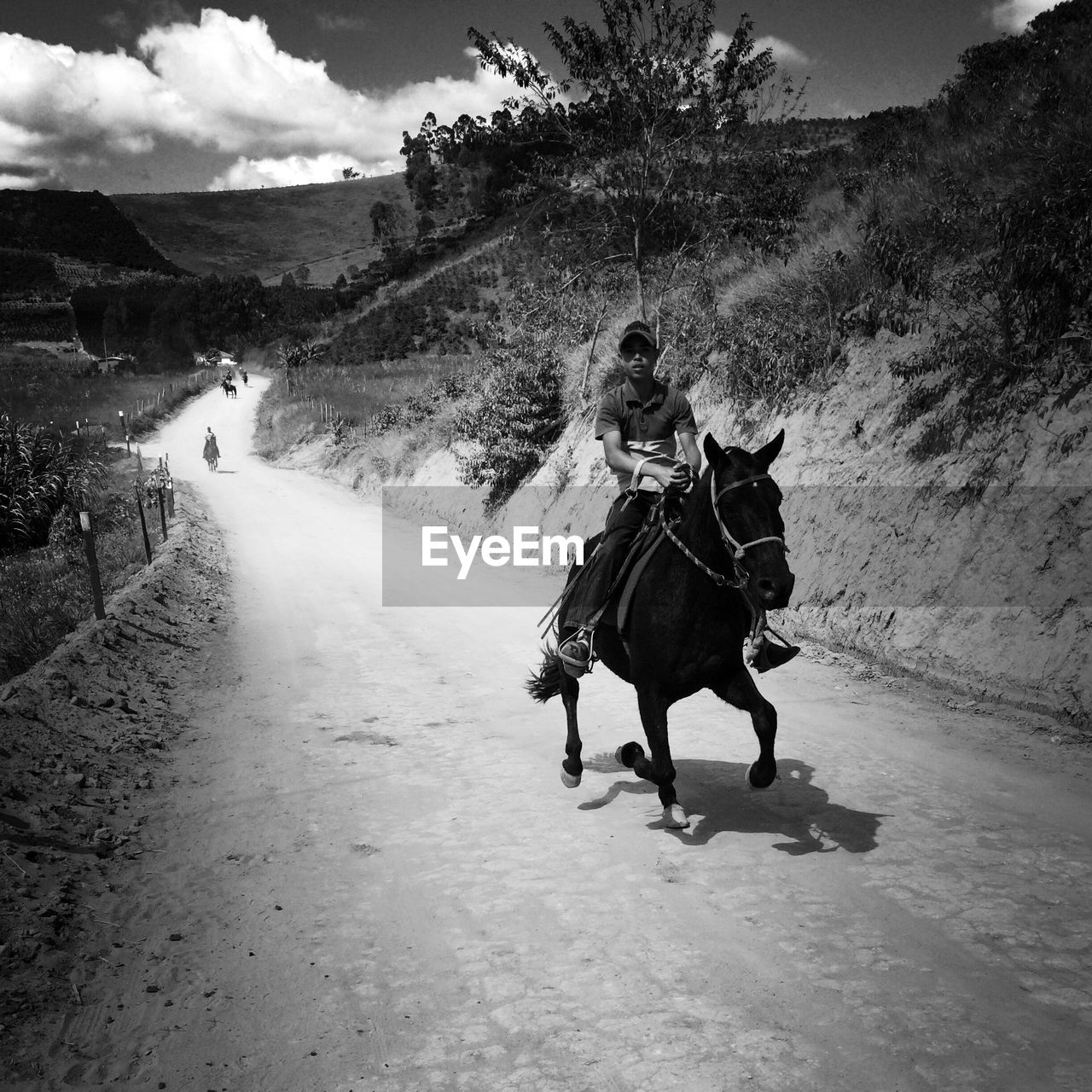 Man riding horse on dirt road by mountain