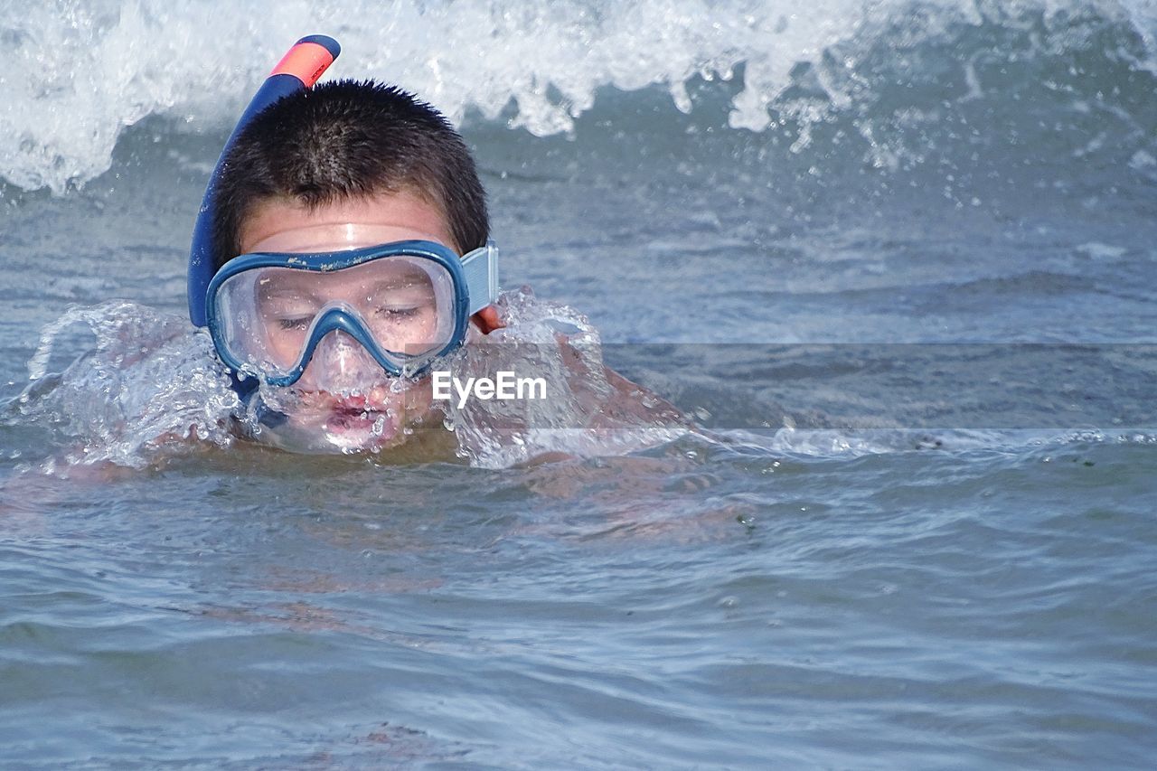 Boy wearing scuba mask while swimming in sea