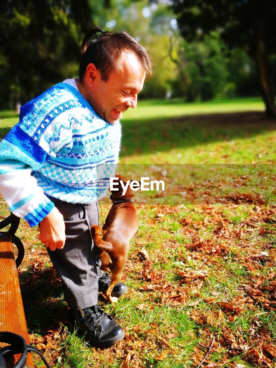 Smiling mature man playing with dog at park