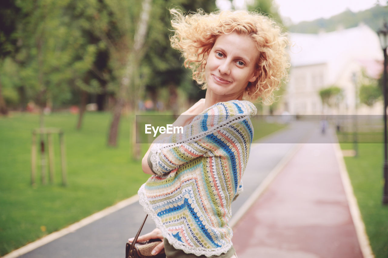 Portrait of woman standing on footpath at park